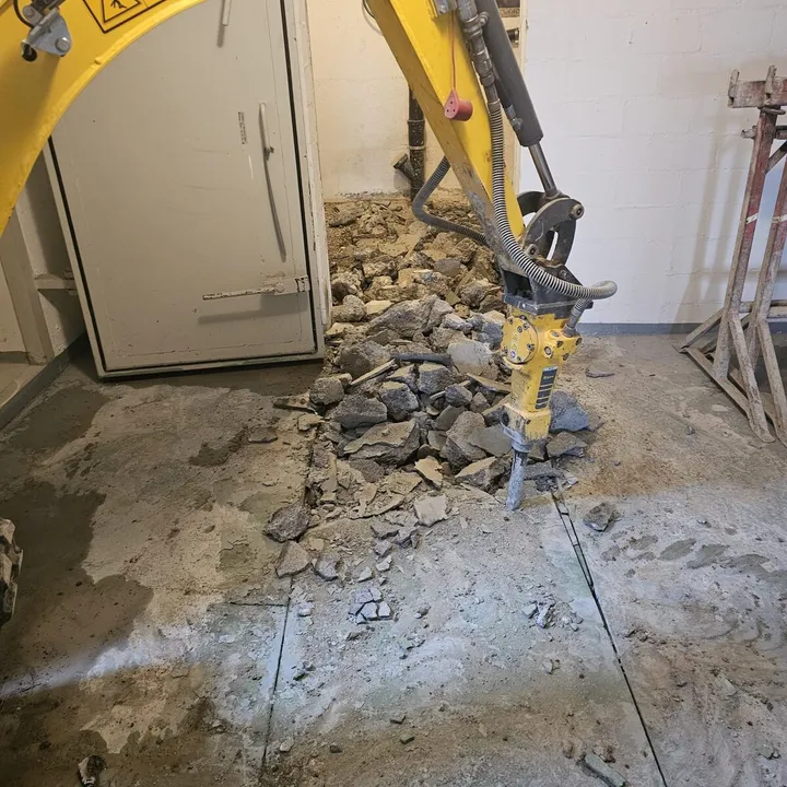 Abbruch eines Betonbodens mit Minibagger im Innenraum