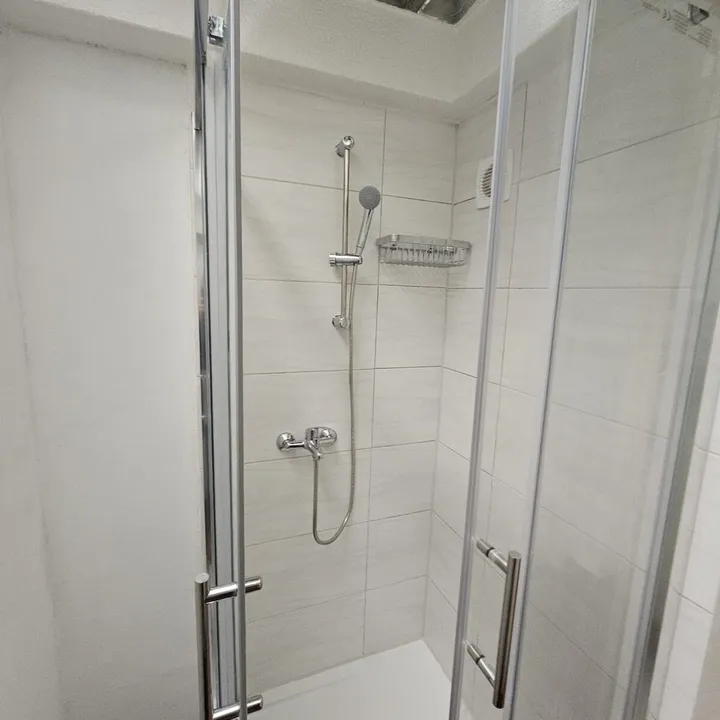 Neue Dusche mit Glastrennwand und montierter Armatur