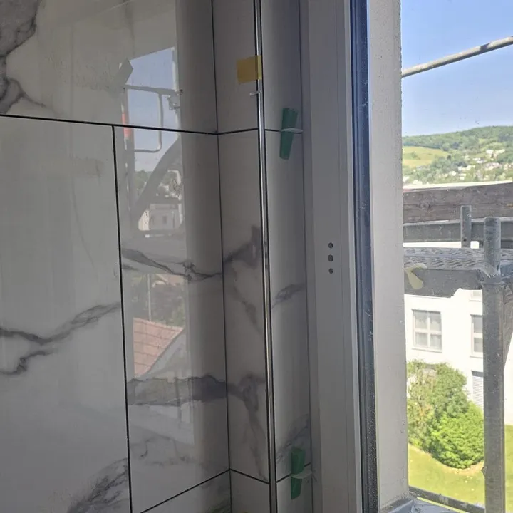 Präzise geflieste Fensterlaibung in Marmoroptik