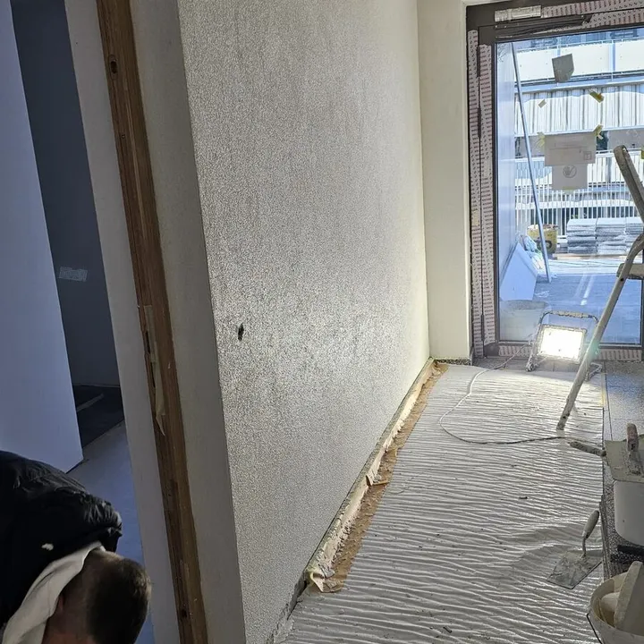 Gipserarbeiten in einem Flur mit abgedecktem Boden