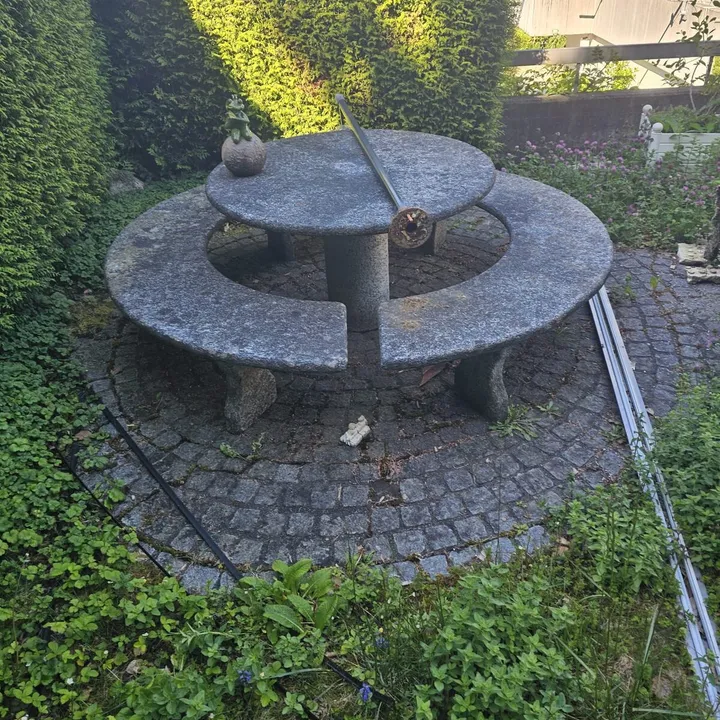 Runder Natursteinbrunnen in einer Gartenanlage